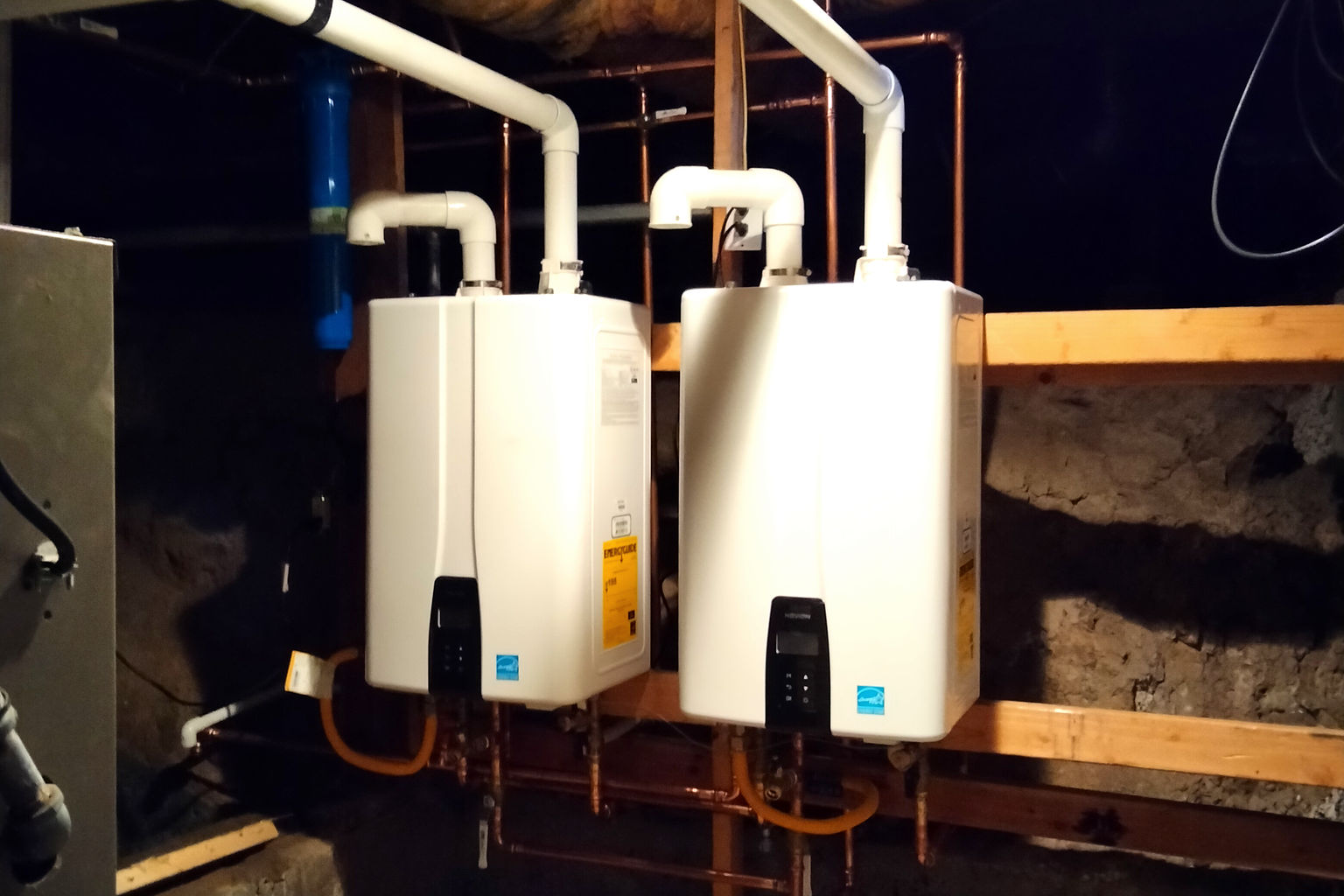 Two Navien tankless units installed in cascade beneath a Sacramento home, vents run overhead and copper supply and gas lines below