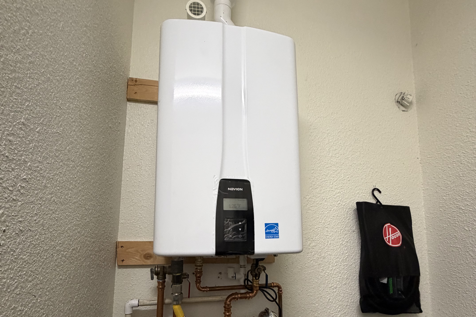 A tankless unit mounted square on a garage wall with lines dressed and labeled